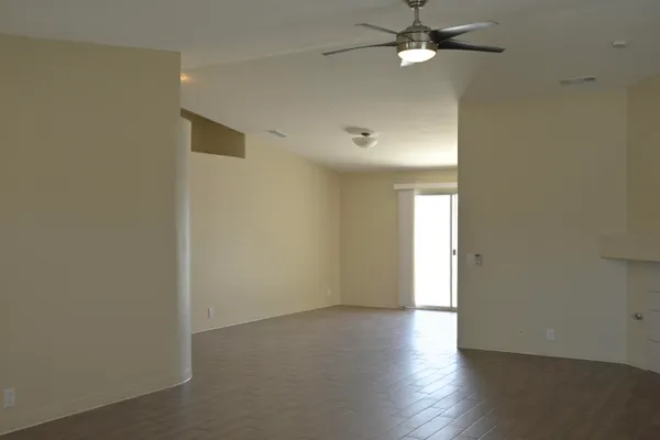 an empty room with wooden floor fan and window
