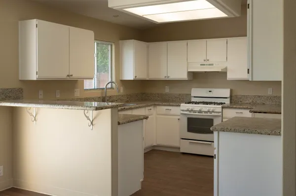 a kitchen with granite countertop white cabinets and white stainless steel appliances