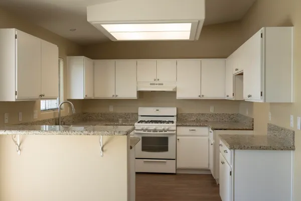 a kitchen with granite countertop white cabinets and white stainless steel appliances
