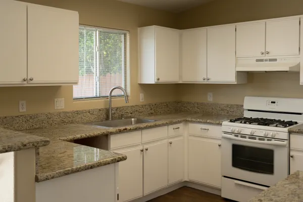 a kitchen with granite countertop white cabinets and white appliances