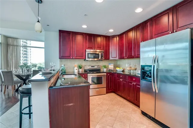 a kitchen with kitchen island granite countertop wooden cabinets a sink a stove and a refrigerator