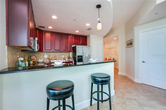 a kitchen with stainless steel appliances granite countertop a sink a stove a refrigerator cabinets and a dining table