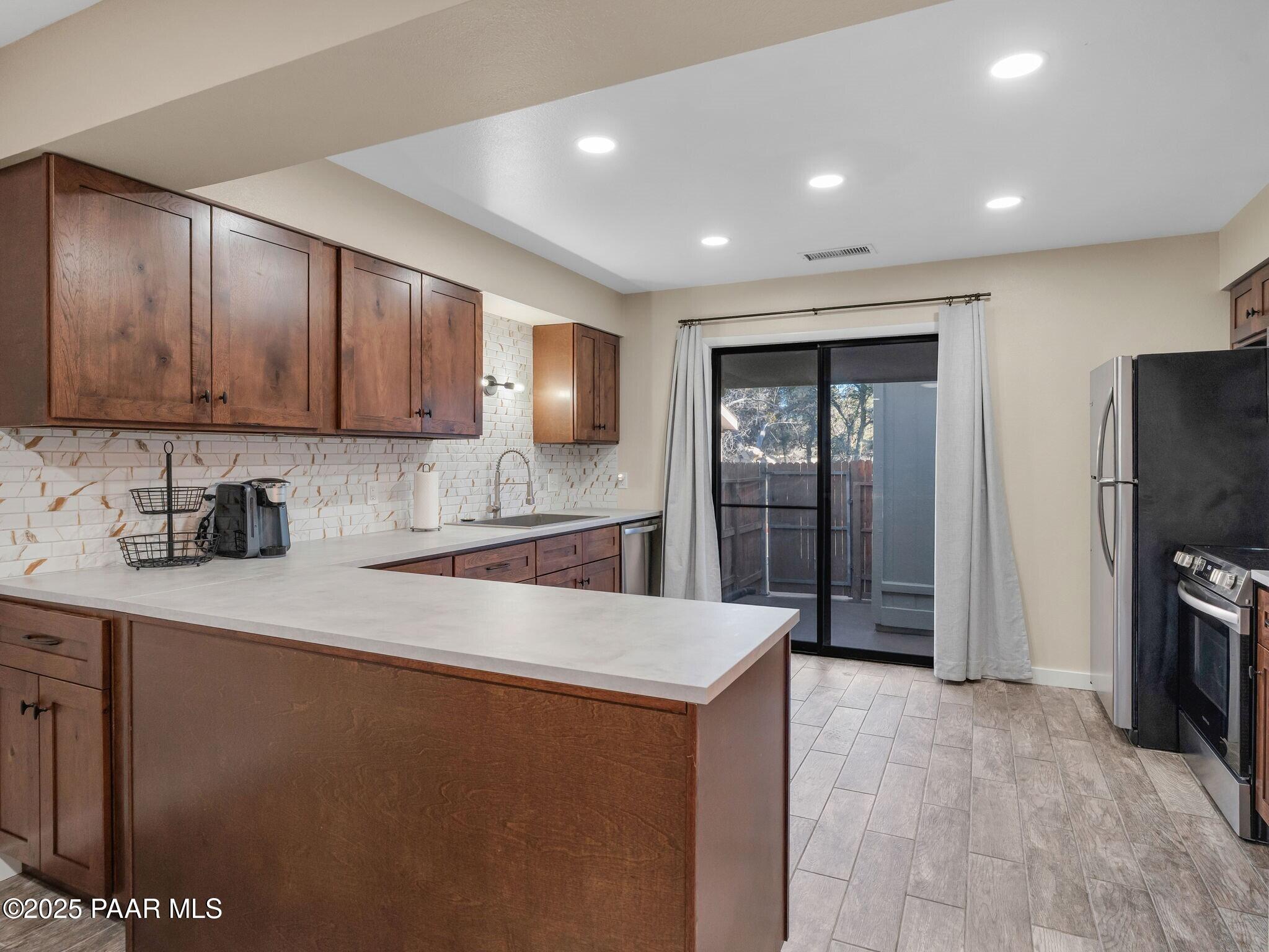 352 Rim Rock Circle, Unit 2 Prescott, AZ 86303 - Photo 13 of 25 a large kitchen with stainless steel appliances granite countertop a refrigerator a sink a stove a microwave and island