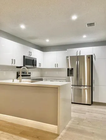 a kitchen with stainless steel appliances granite countertop a refrigerator a stove top oven a sink and dishwasher
