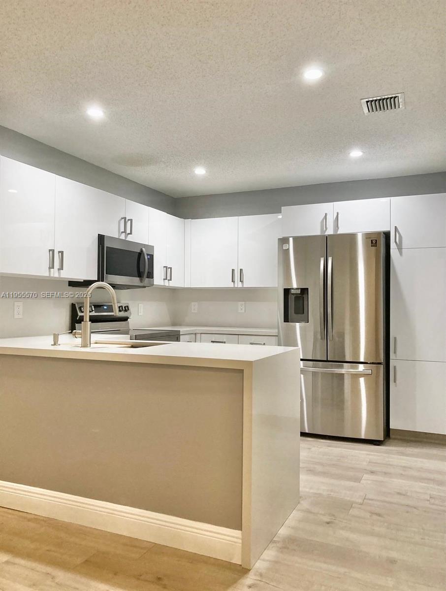 a kitchen with stainless steel appliances granite countertop a refrigerator a stove top oven a sink and dishwasher