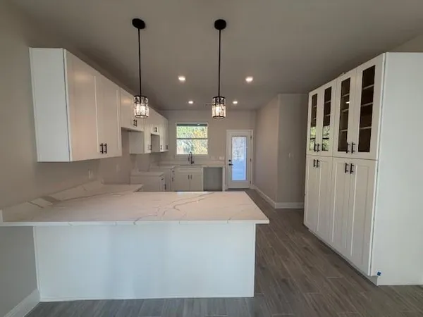 a large kitchen with stainless steel appliances kitchen island a refrigerator and a wooden floor