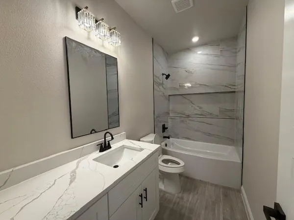 a bathroom with a bathtub shower sink vanity and toilet