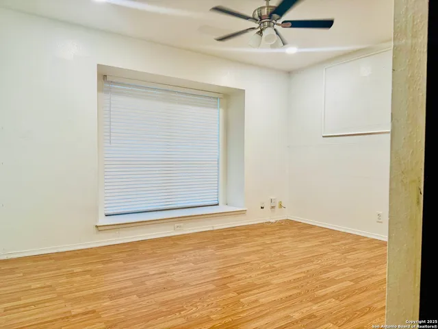 an empty room with a ceiling fan and windows