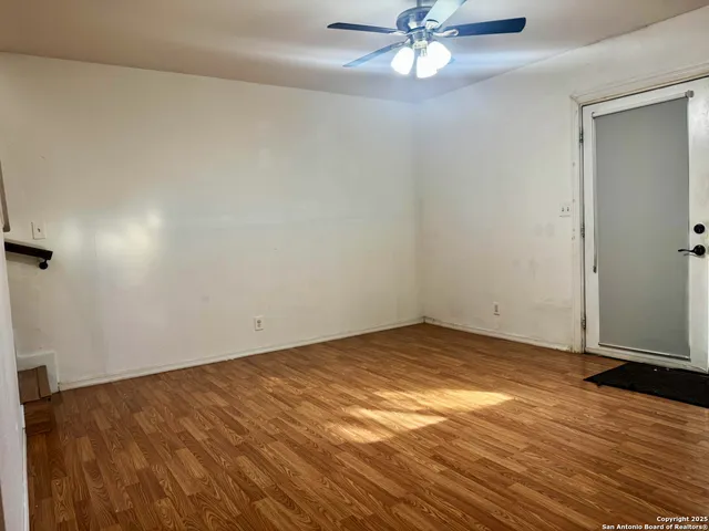 an empty room with wooden floor closet and fan