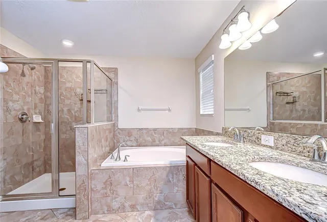 a bathroom with a granite countertop bathtub sink vanity and mirror