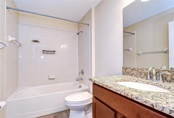 a bathroom with a granite countertop sink a toilet and shower