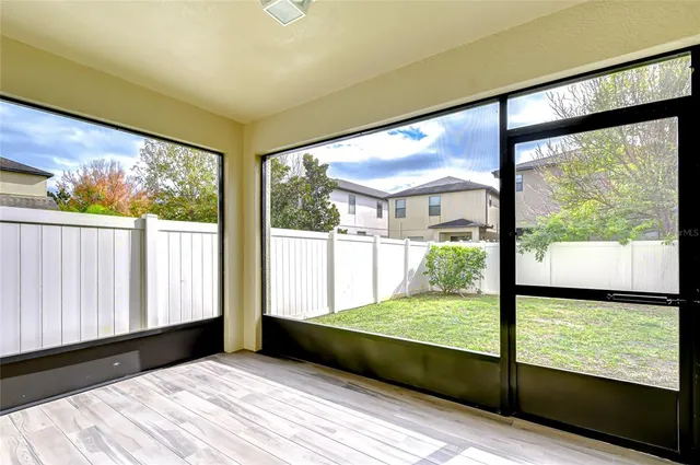 a view of an empty room with wooden floor and a large window with yard
