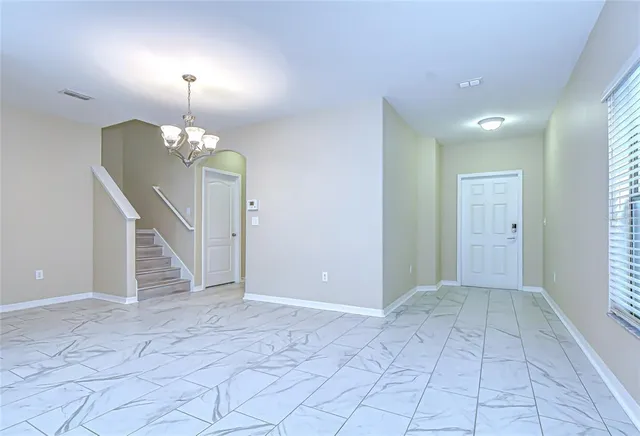 wooden floor in an empty room with a chandelier fan