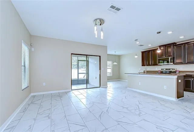 a view of an empty room with kitchen and window