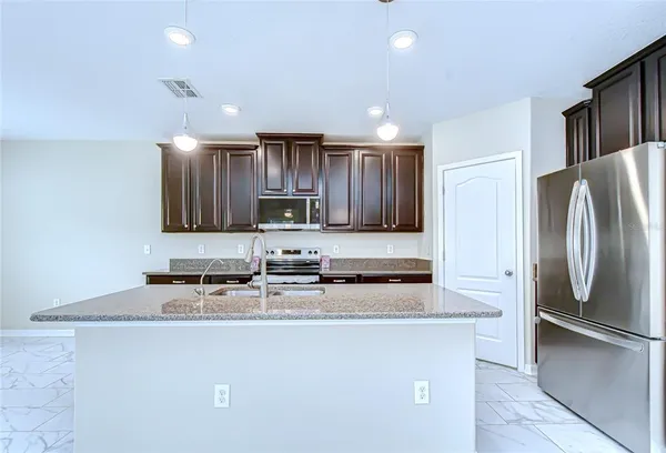 a kitchen with stainless steel appliances granite countertop a refrigerator a stove and a sink