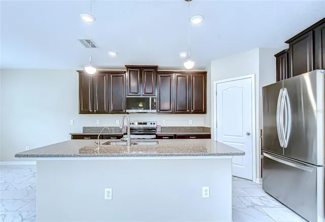 a kitchen with stainless steel appliances granite countertop a refrigerator a stove and a sink