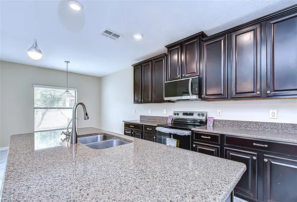a kitchen with stainless steel appliances granite countertop wooden cabinets a stove top oven a sink and dishwasher