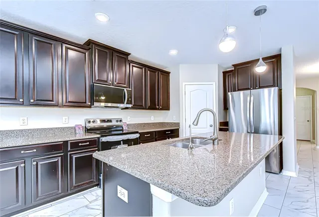 a kitchen with granite countertop a stove sink and refrigerator
