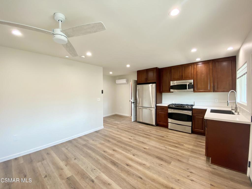 423 Saratoga Street, Unit B Fillmore, CA 93015 - Photo 5 of 20 a kitchen with stainless steel appliances kitchen island granite countertop a stove top oven a sink a refrigerator with wooden floors and cabinets