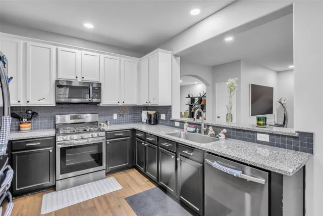 a kitchen with stainless steel appliances granite countertop a sink stove and microwave