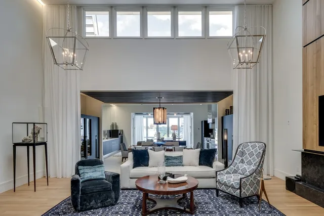 a living room with furniture a chandelier and a dining table with wooden floor