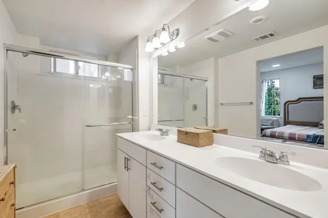 a bathroom with a double vanity sink mirror and shower