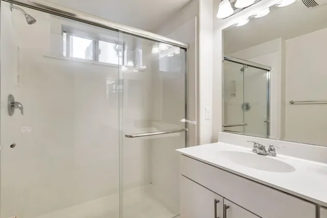 a bathroom with a granite countertop sink mirror and a shower