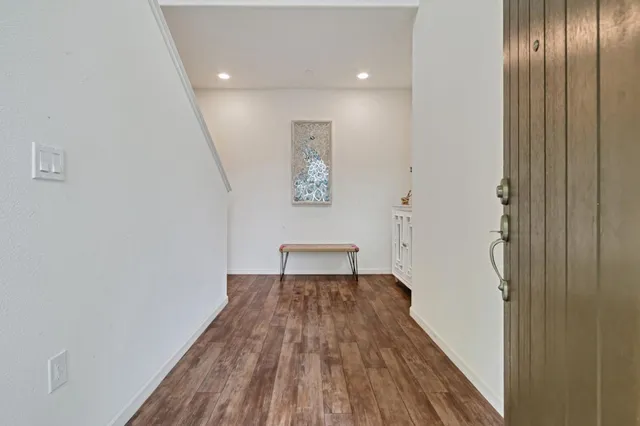 a view of a hallway with wooden floor and a bathroom