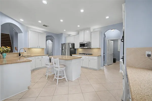 an open kitchen with granite countertop a stove top oven a sink dishwasher a dining table and chairs with wooden floor