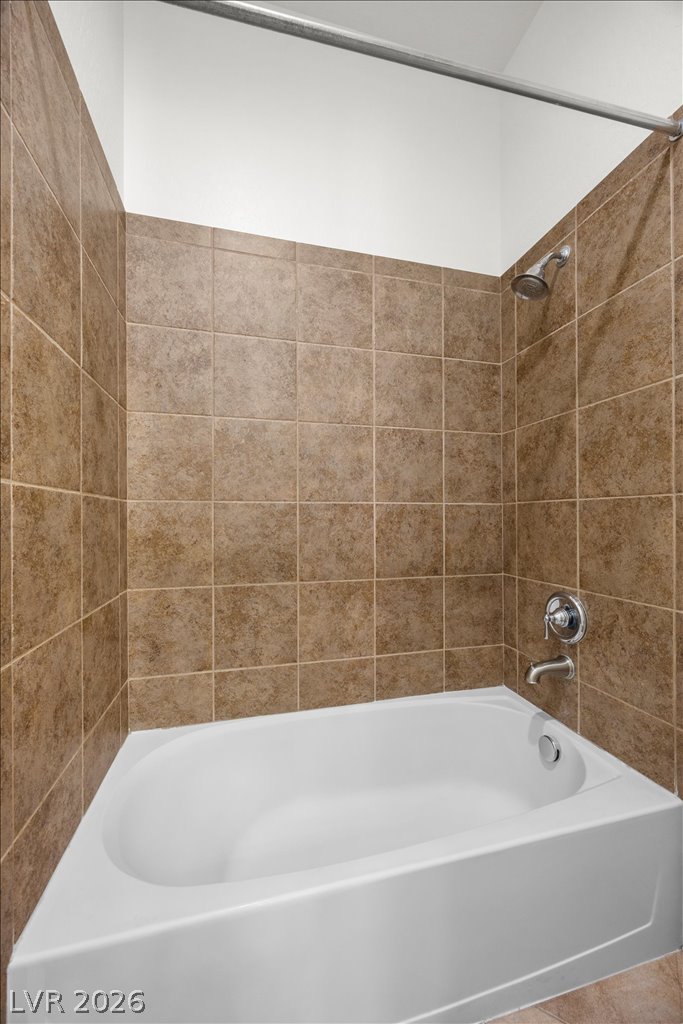 2125 De Rouge Avenue Henderson, NV 89044 - Photo 57 of 96 A well-maintained bathroom with warm-toned tile surrounds a pristine white tub.