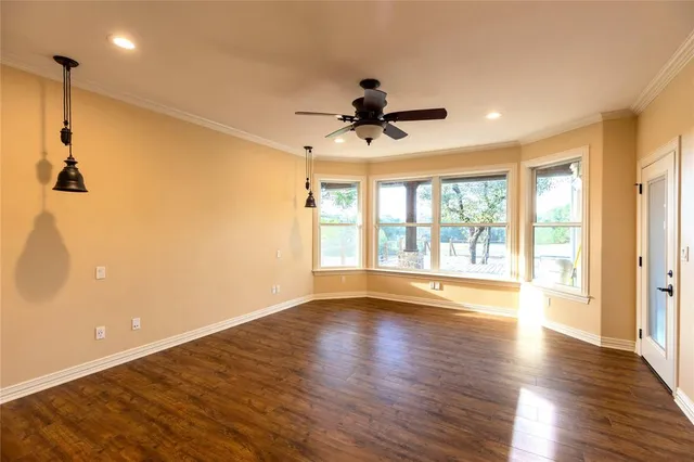 a view of an empty room with a window and wooden floor
