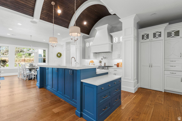 2917 Old Farm Road Washington, UT 84780 - Photo 22 of 105 Two tone kitchen with dual tone cabinetry, a center island with sink, light stone countertops, dark wood finished floors, and decorative light fixtures