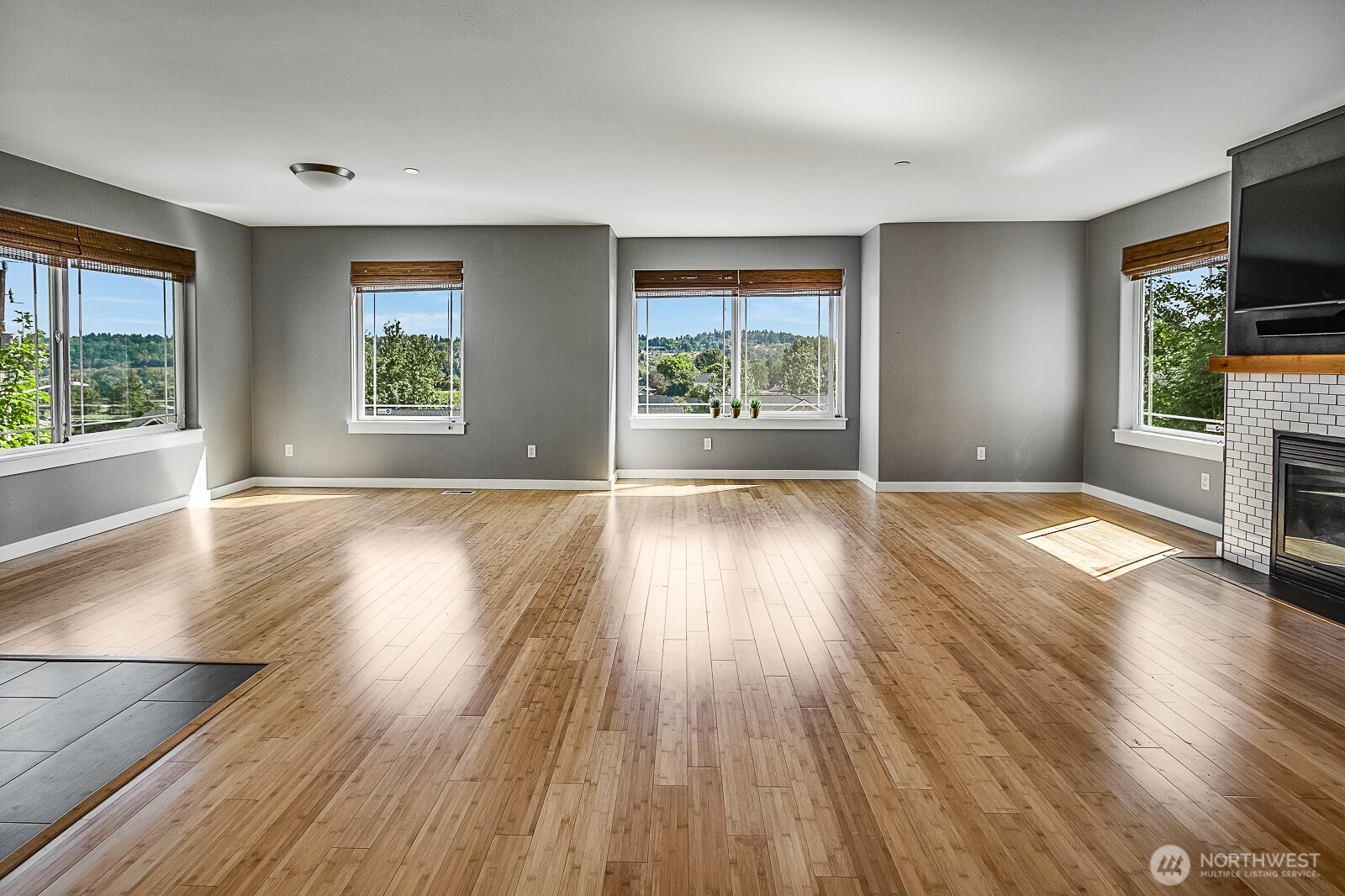 an empty room with wooden floor fireplace and windows