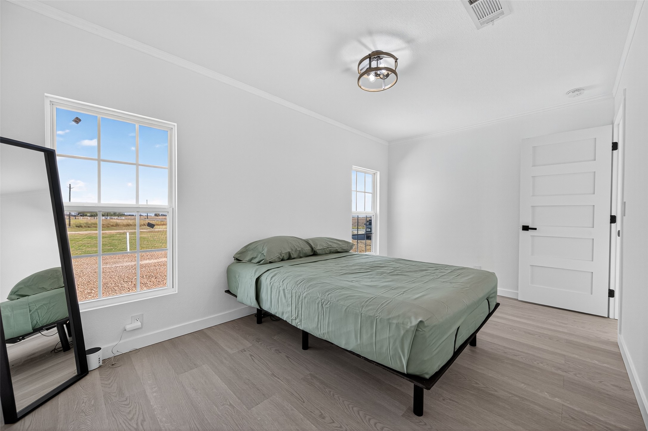 805 Williams Road East Bernard, TX 77435 - Photo 20 of 47 Bedroom featuring neutral tones, modern lighting, and windows with peaceful views of the surrounding acreage.