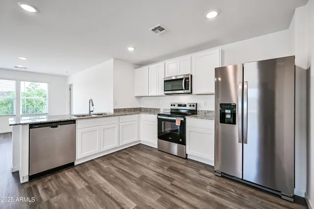 a kitchen with granite countertop a refrigerator stove and microwave