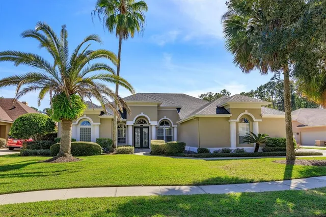 a front view of a house with a garden and trees