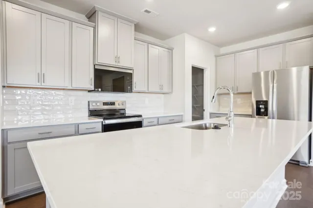 a kitchen with stainless steel appliances a stove a sink a refrigerator white cabinets and a refrigerator