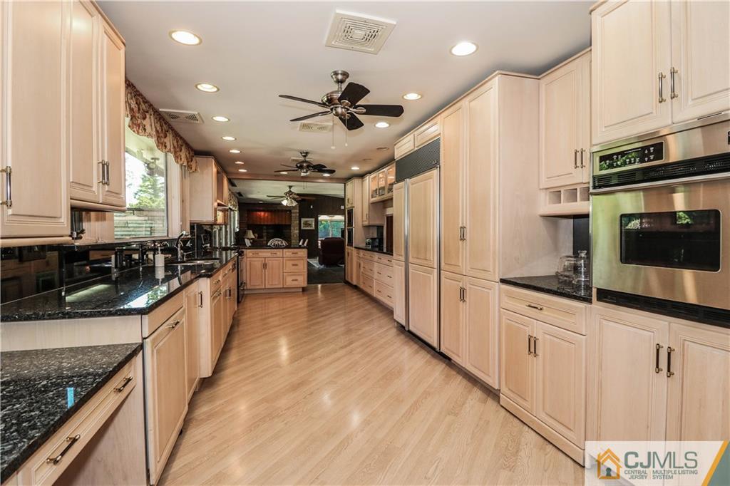 45 Sherwood Road Colonia, NJ 07067 - Photo 10 of 25 a large kitchen with stainless steel appliances kitchen island granite countertop a lot of counter space and wooden floor