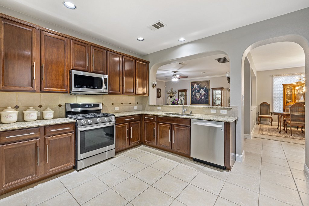10800 Desert Willow Loop Austin, TX 78748 - Photo 10 of 36 a kitchen with stainless steel appliances granite countertop a stove top oven a sink dishwasher and a microwave oven on the blue kitchen countertops