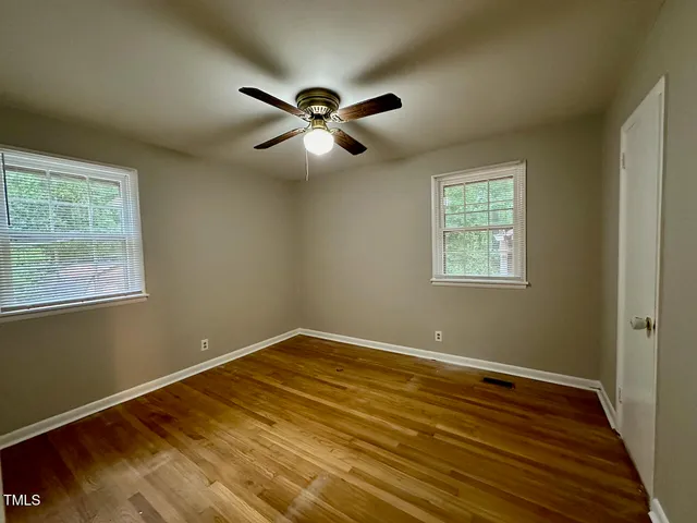 a view of empty room with wooden floor and fan
