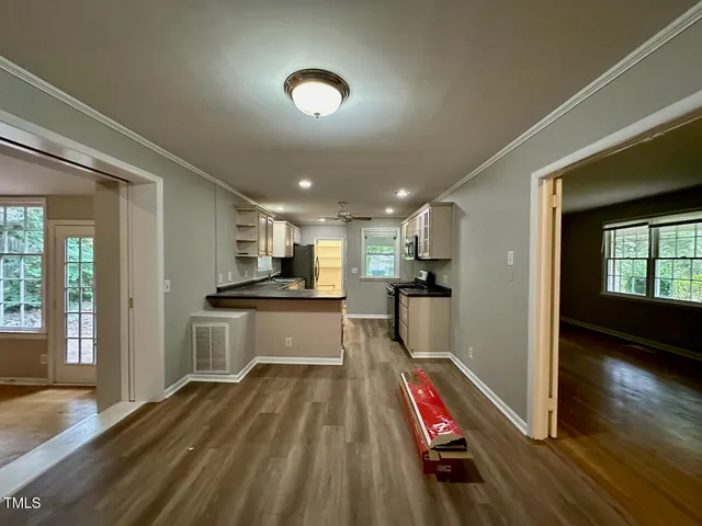 a room with wooden floor and view of kitchen