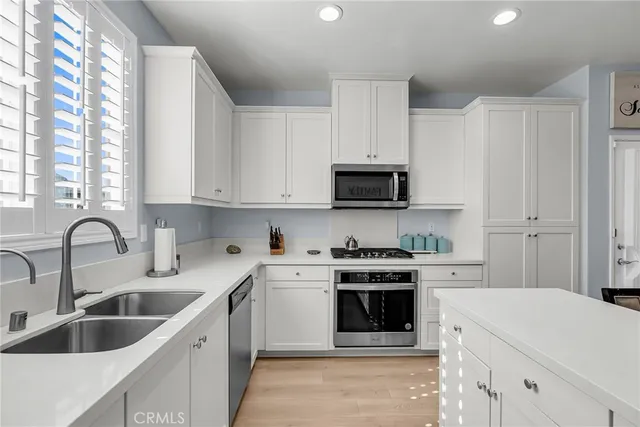 a kitchen with white cabinets a sink and white appliances