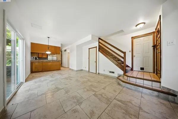 a view of an empty room and a kitchen