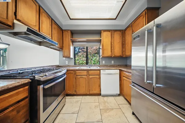 a kitchen with stainless steel appliances granite countertop a stove a sink and a refrigerator