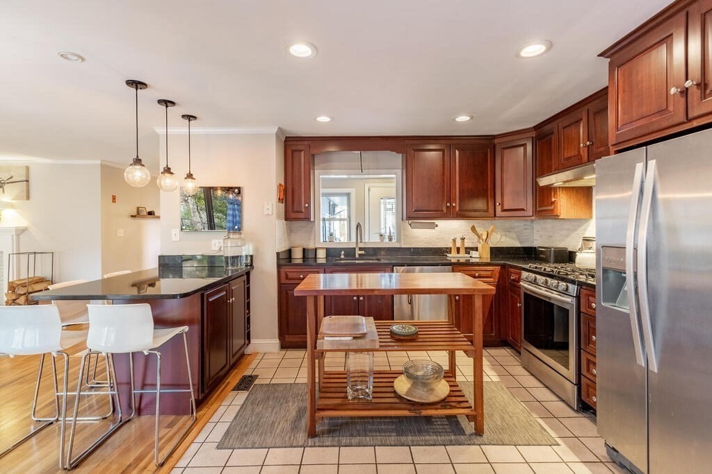 15 Forrest Road Topsfield, MA 01983 - Photo 7 of 26 a kitchen with stainless steel appliances granite countertop a stove top oven a sink dishwasher a dining table and chairs with wooden floor