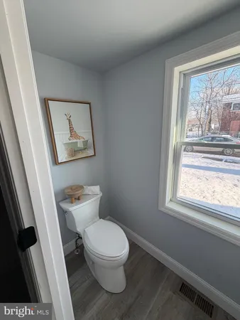 a white toilet sitting next to a window in a bathroom