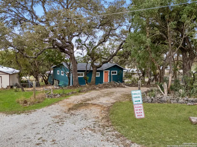 a front view of a house with a yard and large trees