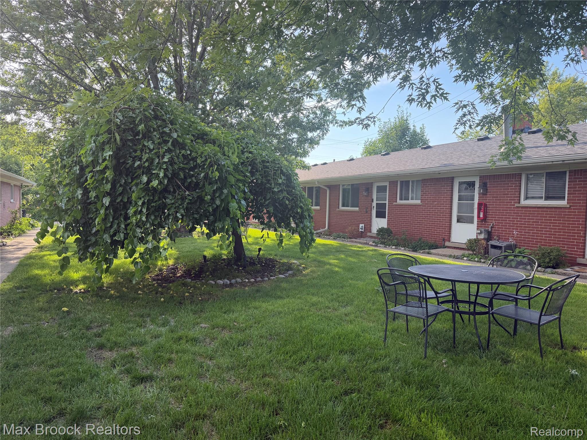 3875 Devon Road, Unit # 9 Royal Oak, MI 48073 - Photo 2 of 17 Expansive green lawn featuring a mature weeping tree with an established stone-lined bed