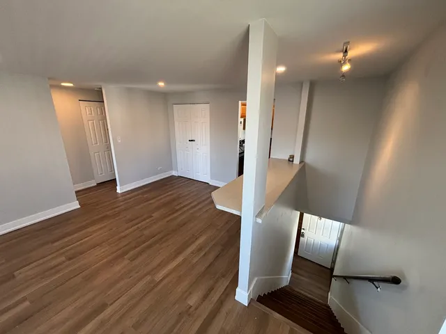 a view of a hallway with wooden floor and staircase