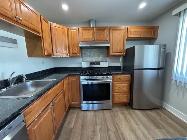 a kitchen with granite countertop wooden cabinets stainless steel appliances and a sink